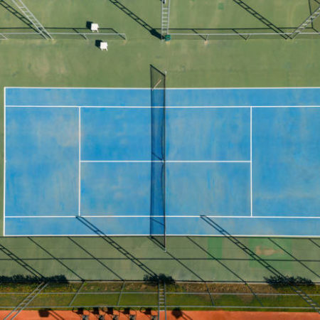 Pourquoi est-il important de maintenir une certaine porosité dans le béton utilisé pour les courts de tennis ?