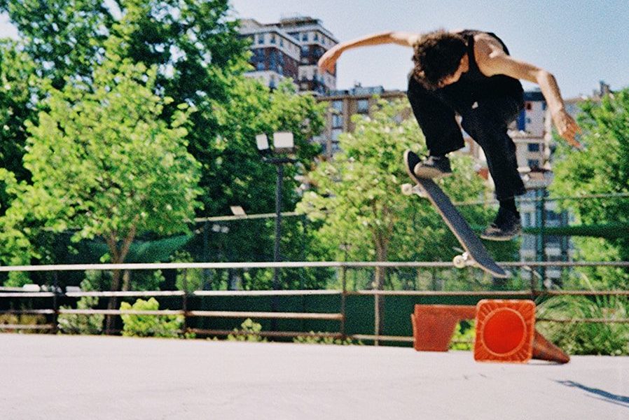 A skateboarder performs an aerial trick in an outdoor park.
